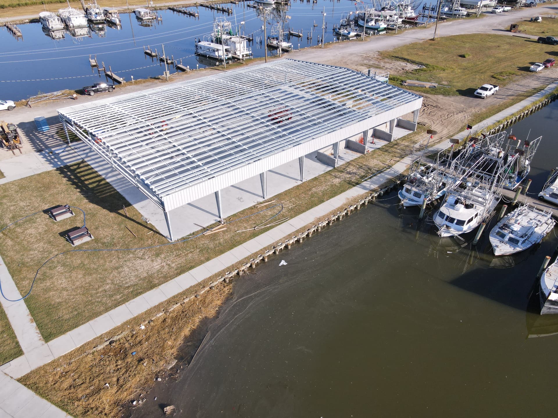 Steel framing of a boathouse under construction along a working waterfront