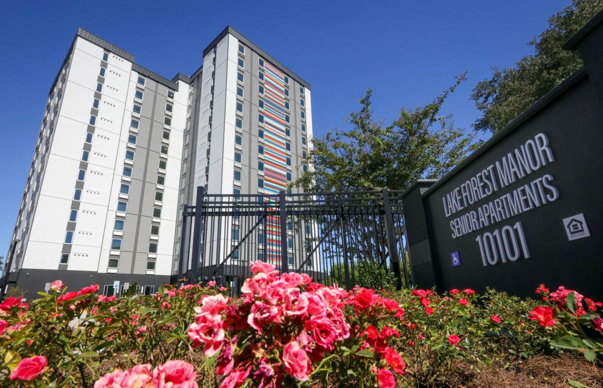 High-rise senior apartment tower behind a landscaped garden sign