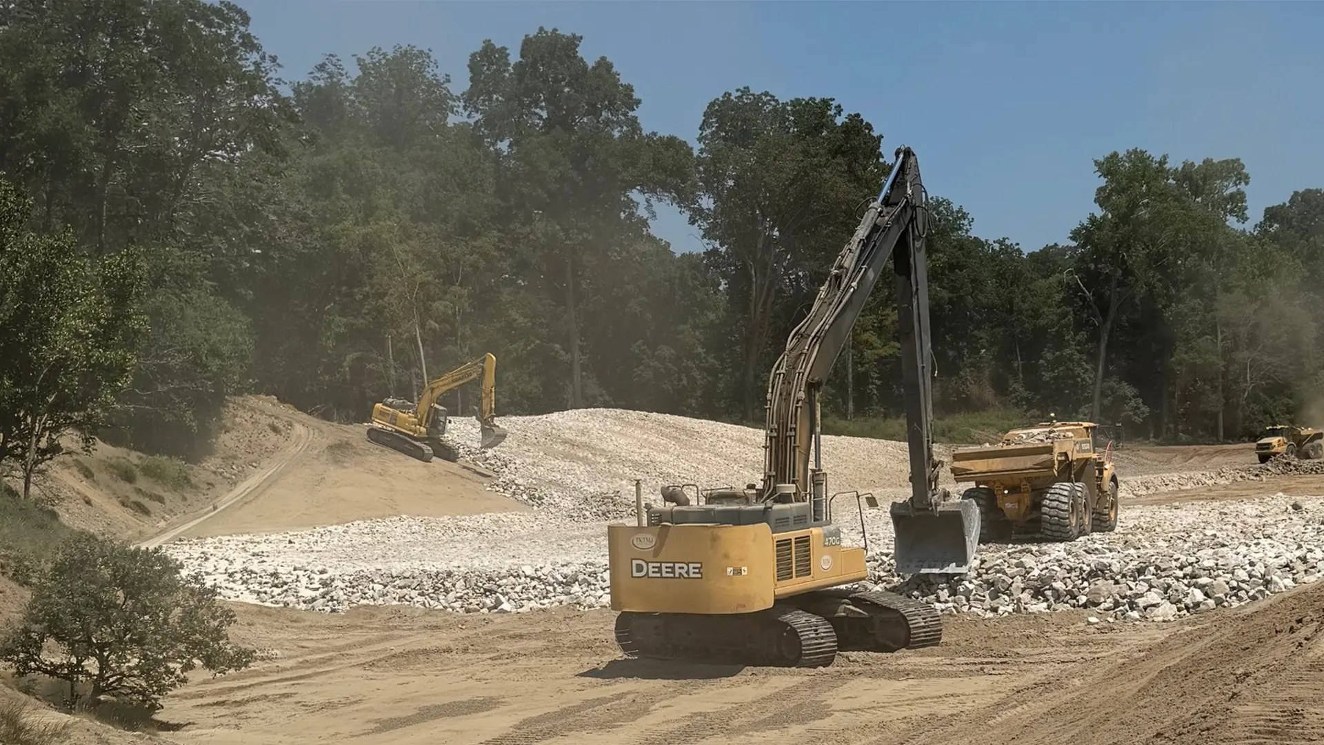 Excavator and haul truck working a rock embankment