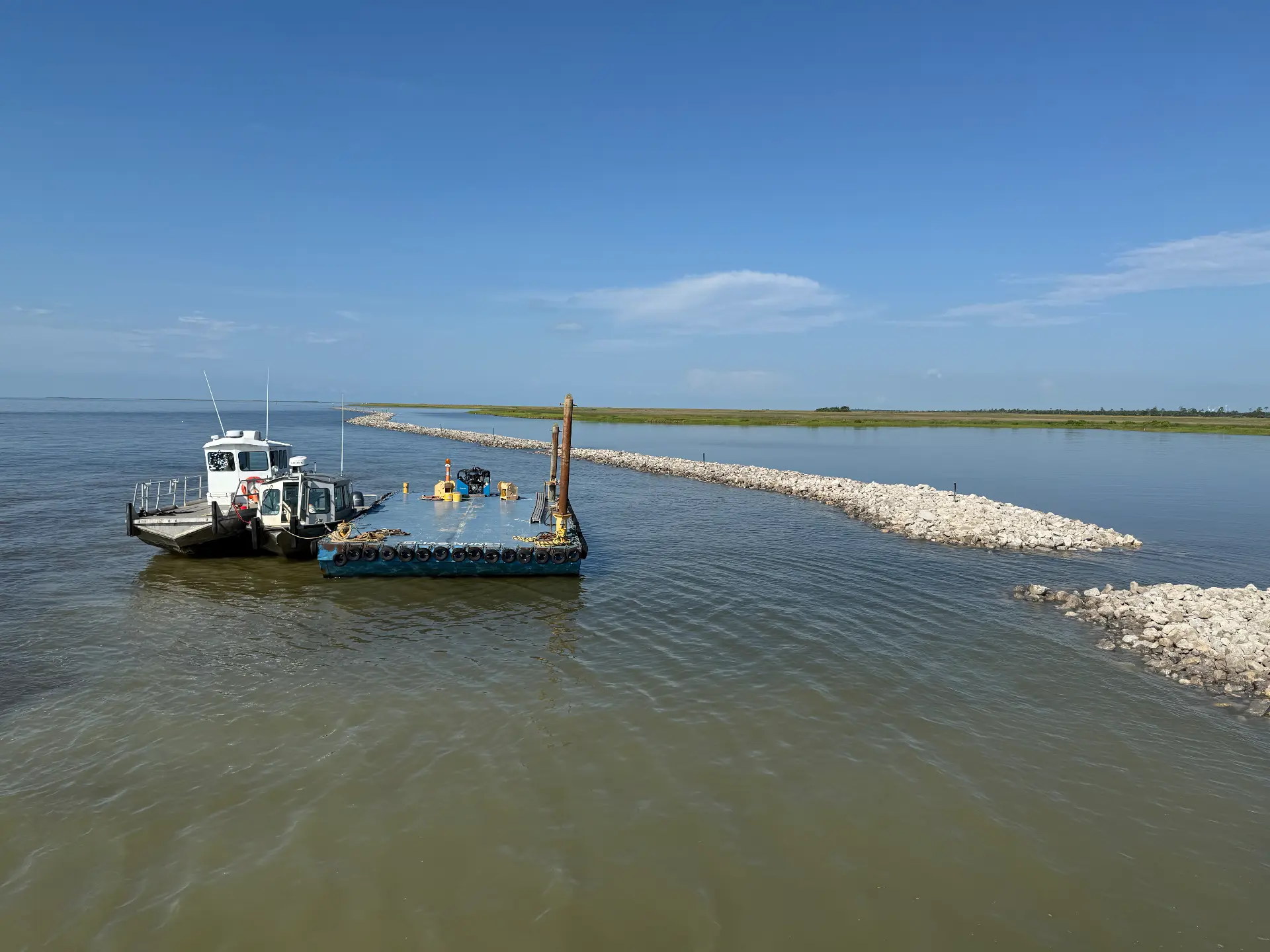 Tug and material barge working along a rock breakwater at open water