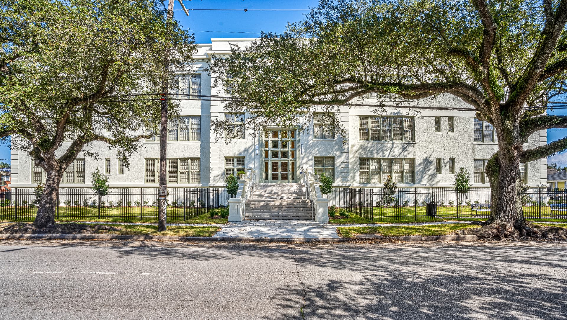 Front facade of a restored historic building framed by live oak trees