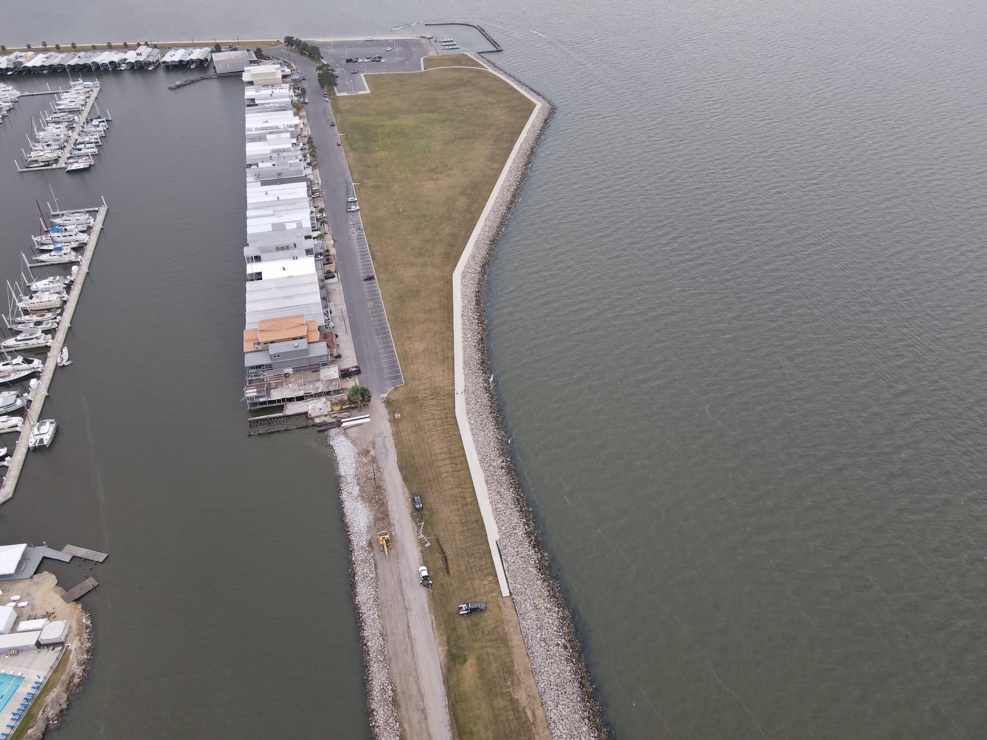 Aerial view of a stone shoreline revetment protecting a waterfront road and marina