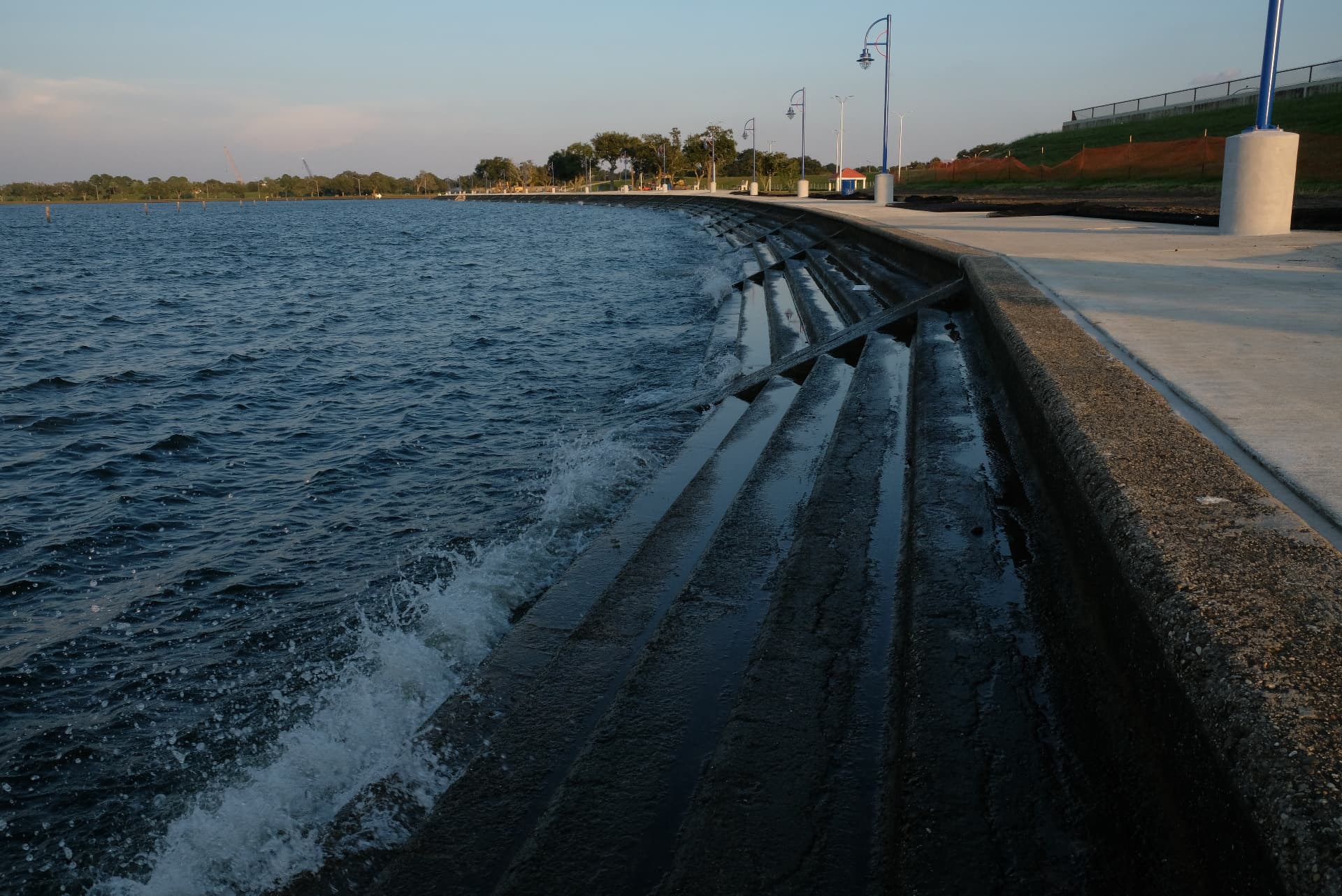 Stepped concrete seawall with waves breaking against it at dusk