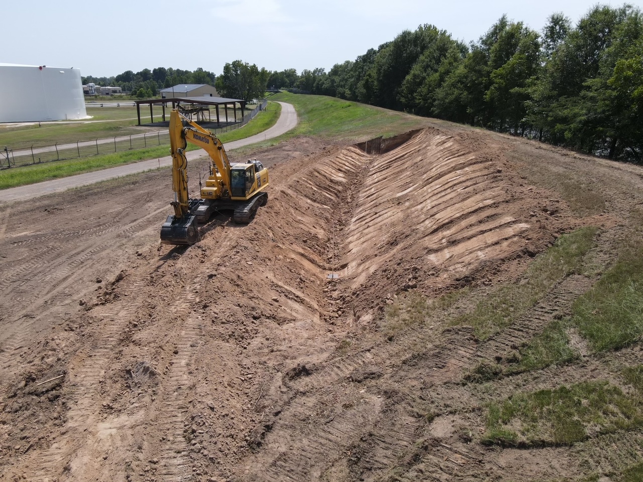 Excavator cutting a channel along a levee slope